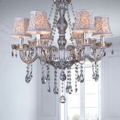 a chandelier hanging from the ceiling in a room with white walls and windows