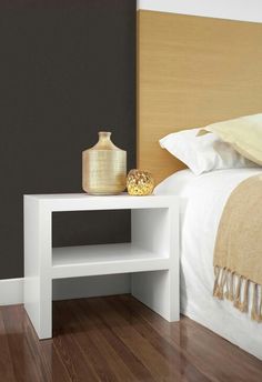 a white table sitting on top of a hard wood floor next to a neatly made bed