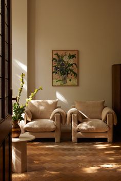 a living room with two couches and a vase on the wall next to it