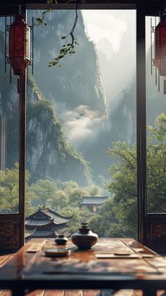 a table with two tea cups on it in front of a window overlooking the mountains