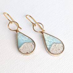 These light teardrop dangle earrings have been mixed with real sand and hand colored eco-resin, mixed with crushed stones and silver specks and poured/painted individually. The body and wiring is made in jewelers brass. If you prefer the wiring that will touch your ears made out of 14 K Filled wire, please use the Made to order option with 14 K Gold Filled Ear Wiring (Additional+$8.00). Each earring measures approx. 1.25 inch high and hangs at about 1.75 inches from the ear. Made to order option Resin Jewlery, Coastal Jewelry, Wood Resin Jewelry, Resin Jewelry Diy, Beach Earrings, Resin Ideas, Eco Resin, Earrings Summer, Beach Necklaces