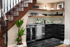 a kitchen with stainless steel appliances and black tile flooring next to a stair case