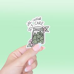 a hand holding up a sticker with a jar full of cacti in it