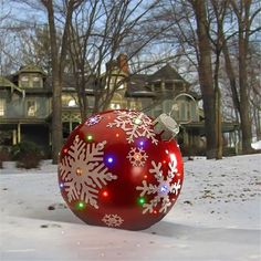 a red ornament with snowflakes on it sitting in the snow outside