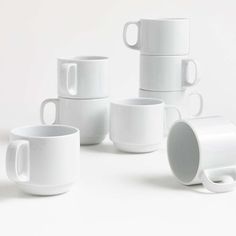 several white coffee cups stacked on top of each other with one cup in the middle