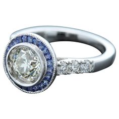 Art Deco Style Bold Ring Center is 1.25 carat Diamond surrounded with Blue Sapphire, sides have regular small white Diamonds All stones are Natural 18k White 5.70 grams Center Diamond is a Brilliant J-K color and SI2-I1 clean however has a very good sparkle (8.0 mm) set in a cup setting Small Diamonds 0.37 carat Blue Sapphire 0.63 carat Finger size 7 overall surface area diameter size - 12mm Dazzling Round Sapphire Ring With Vvs Clarity, Dazzling Sapphire Ring With Vvs Clarity, Dazzling Multi-stone Platinum Diamond Ring, Gia-certified Cluster Sapphire Ring With Diamond, White Gold Multi-stone Round Sapphire Ring, Gia Certified Cluster Sapphire Ring With Diamond, Multi-stone Round Sapphire Ring In Platinum, Luxury Gia Certified Diamond White Sapphire Ring, Gia Certified Sapphire Cluster Jewelry