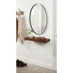 a mirror on the wall above a shelf with a plant and other items in front of it