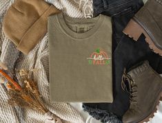 Left chest embroidered Pumpkin outline with Hello Fall.   This is a premium tee from Comfort Colors. Photo shows the shirt color in Khaki, Pepper and Yam.  Stitched in vibrant autumn colors, browns, pumpkin, moss green and ivory, it screams Fall and Autumn!    - Comfort Colors Unisex sizing - Embroidered design Please message me with any questions! Casual Embroidered Fall T-shirt, Casual Embroidered T-shirt For Fall, Green Tops With Embroidered Logo For Fall, Casual Fall T-shirt With Embroidered Logo, Casual Embroidered Logo T-shirt For Fall, Fall Embroidered Graphic Tee, Fall Short Sleeve T-shirt With Embroidered Logo, Fall Crew Neck Tops With Machine Embroidery, Embroidered Graphic Tee For Fall