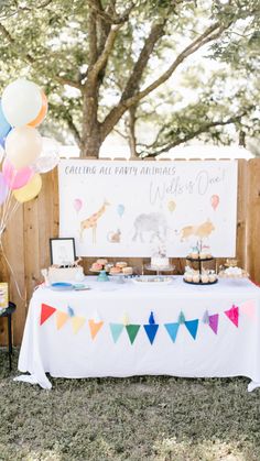 a birthday party with balloons, cake and desserts on a table in front of a fence