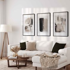 a living room with white furniture and paintings on the wall