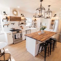 a kitchen with white cabinets and wooden counter tops, an island in the middle is surrounded by stools