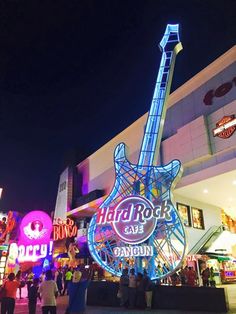 a guitar shaped sign is lit up in the night sky at hard rock cafe and casino