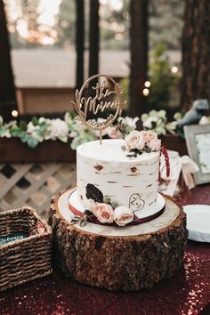 a white wedding cake sitting on top of a tree stump