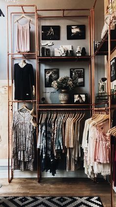 an open closet with clothes and pictures on the wall, including shirts hanging from metal racks