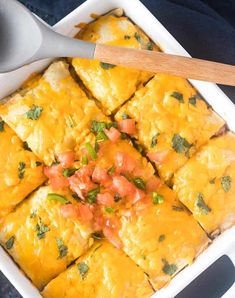 a casserole dish with cheese, tomatoes and cilantro on the side