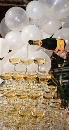 champagne being poured into wine glasses in front of balloons