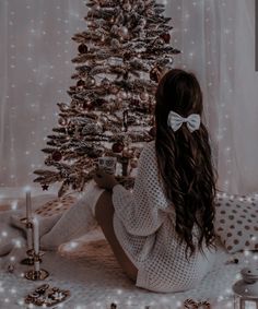 a woman sitting in front of a christmas tree