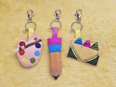 three keychains with different designs on them and one has a pencil in it