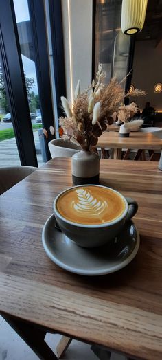 a cappuccino sits on a table in front of a window