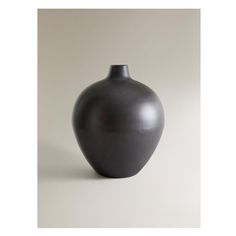 a large gray vase sitting on top of a table next to a white wall and floor