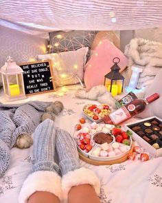 a person laying on top of a bed covered in food and drinks next to a lantern