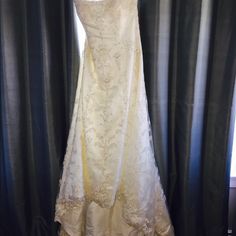 a white wedding dress hanging on a curtain