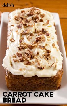 carrot cake bread with cream cheese frosting and pecans on top, sitting on a white plate