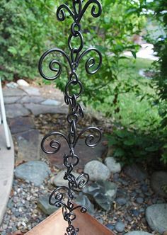 a metal plant stand sitting on top of a wooden table next to rocks and trees