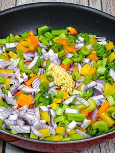 a pan filled with chopped vegetables on top of a wooden table