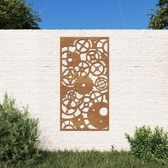 a white brick wall with an intricate cutout on the side and bushes in front