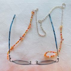 Elegant Beaded Eyeglass Chain Sunglass Strap Unisex Eyeglass Holder Reading Retainer Strap Silver Toned Chain Orange Fine Seed Beads & Chips Length: 29.5in Versatile Eyeglasses Chains: Which Are Suitable For Sunglasses, Reading Glasses, Masks And So On. These Gorgeous Beaded Eyeglass Chains Prevent Your Glasses From Getting Lost. Lightweight Material: These Elegant Eyewear Retainer Chains And Beads Are Made Of High Quality Materials. Handcrafted By Norclar Custom-Made Jewelry & Accessories Adjustable Silver Glasses Chains With Colorful Beads, Beaded Clear Glass Glasses Chains, Clear Beaded Glass Glasses Chains, Silver Glass Beaded Necklace With Colorful Beads, Silver Beaded Necklace With Colorful Glass Beads, Silver Glass Jewelry With Colorful Beads, Silver Jewelry With Colorful Glass Beads, Silver Beaded Glass Chain For Glasses, Silver Beaded Glasses Chains For Beach