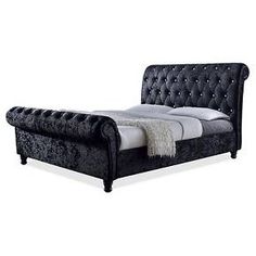 the bed is made up with black velvet and white linens, but no headboard or foot board