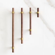 three wooden pegs are lined up on a white marble surface with gold colored handles