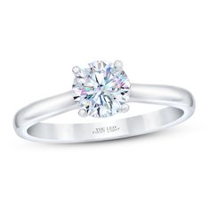 a white gold engagement ring with a round brilliant cut diamond in the center, on a plain surface