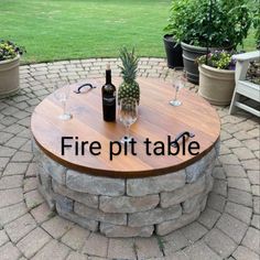 there is a fire pit table with wine glasses on it and pineapple in the middle