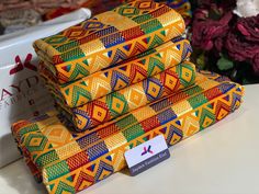 a stack of brightly colored cloths sitting on top of a table next to flowers