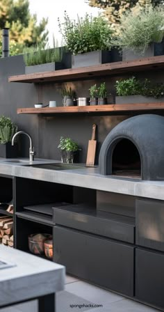 an outdoor kitchen with potted plants on the counter and wood burning oven in the back