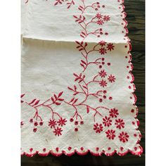 two pieces of cloth with red and white flowers on them, sitting on a wooden table