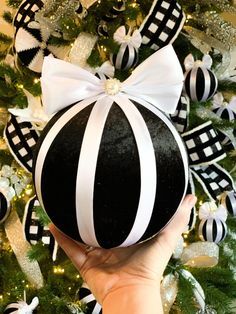 black and white christmas ornament being held up in front of a tree