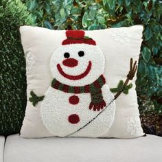 a snowman pillow sitting on top of a white couch next to a green bush