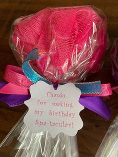 pink and purple birthday cake wrapped in cellophane with tags on it's handles