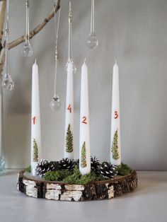 four candles with numbers on them are sitting in front of a tree branch and glass ornament