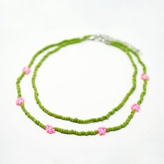 Set of 2, Separate Necklaces Color: Green, Pink Material: Glass Bead Dimensions: 15"-17.5"L for inner necklace, 17.5"-20"L for outter daisy necklace Adjustable Flower Necklace With Round Beads For Spring, Trendy Tiny Beads Necklace For Spring, Green Round Beads Necklaces For Spring, Green Necklaces With Round Beads For Spring, Handmade Green Beaded Necklace For Spring, Spring Green Necklace With Round Beads, Spring Flower Charm Necklace With Round Beads, Trendy Green Necklace For Spring, Green Adjustable Flower Beaded Necklaces