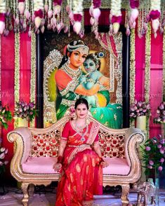 a woman sitting on top of a couch in front of a wall covered with flowers