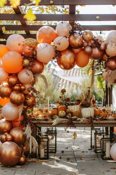 an outdoor table set up with balloons and pumpkins for a fall party or celebration