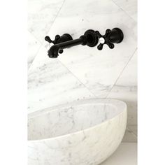 a white marble bowl sink with black faucet and two handles on the wall