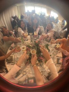 a group of people sitting at a table with wine glasses in their hands and plates on the table