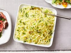 two plates with meat, rice and vegetables next to each other on a gray table cloth