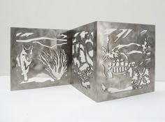 two metal boxes sitting side by side on a white surface with an image of animals and plants