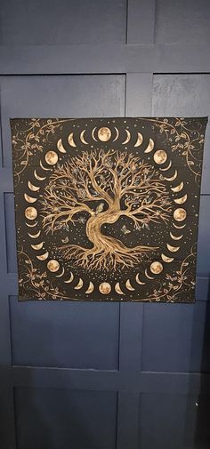 a painting with a tree on it and moon phases in the sky above it, against a blue wall